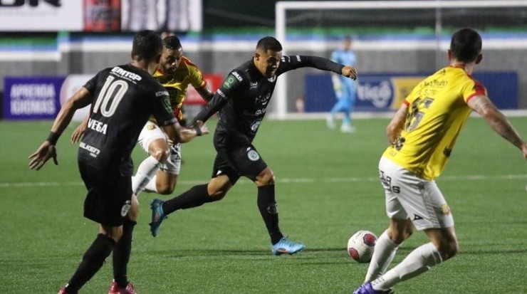 Róger Rojas (Sporting) despeja el balón mientras la marca herediana se mantiene atenta (Sporting FC)